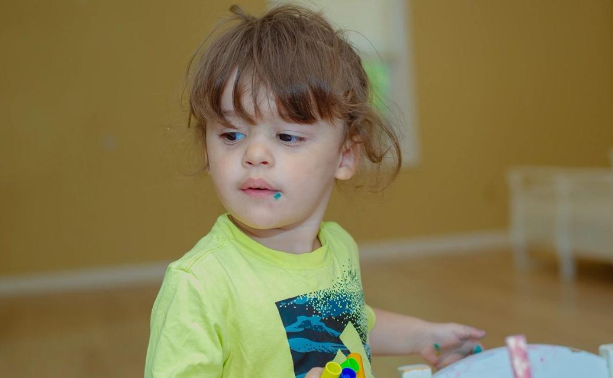 A toddler exploring materials at the classroom table