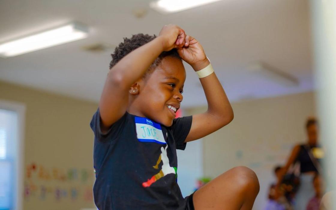 A boy cheering with his arms raised in the classroom