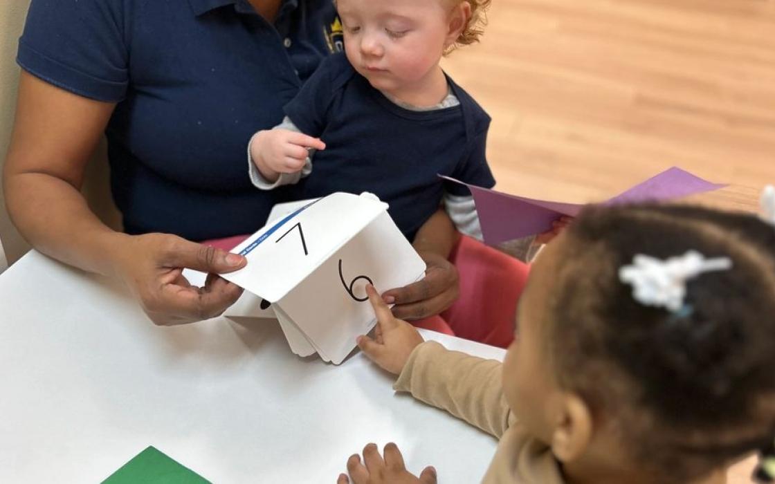 A teacher and toddler working on a craft together