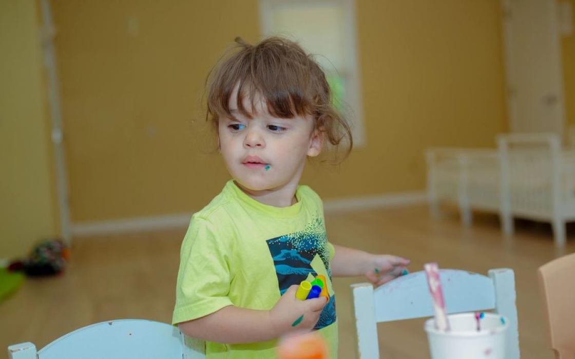 A toddler pouring and measuring at the activity table