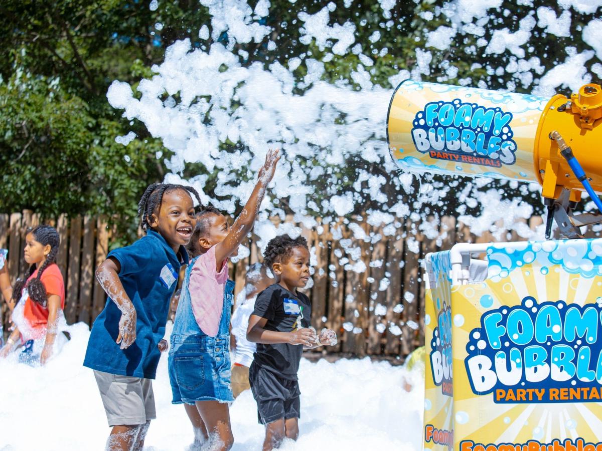Children reaching toward a foam cannon at a family event