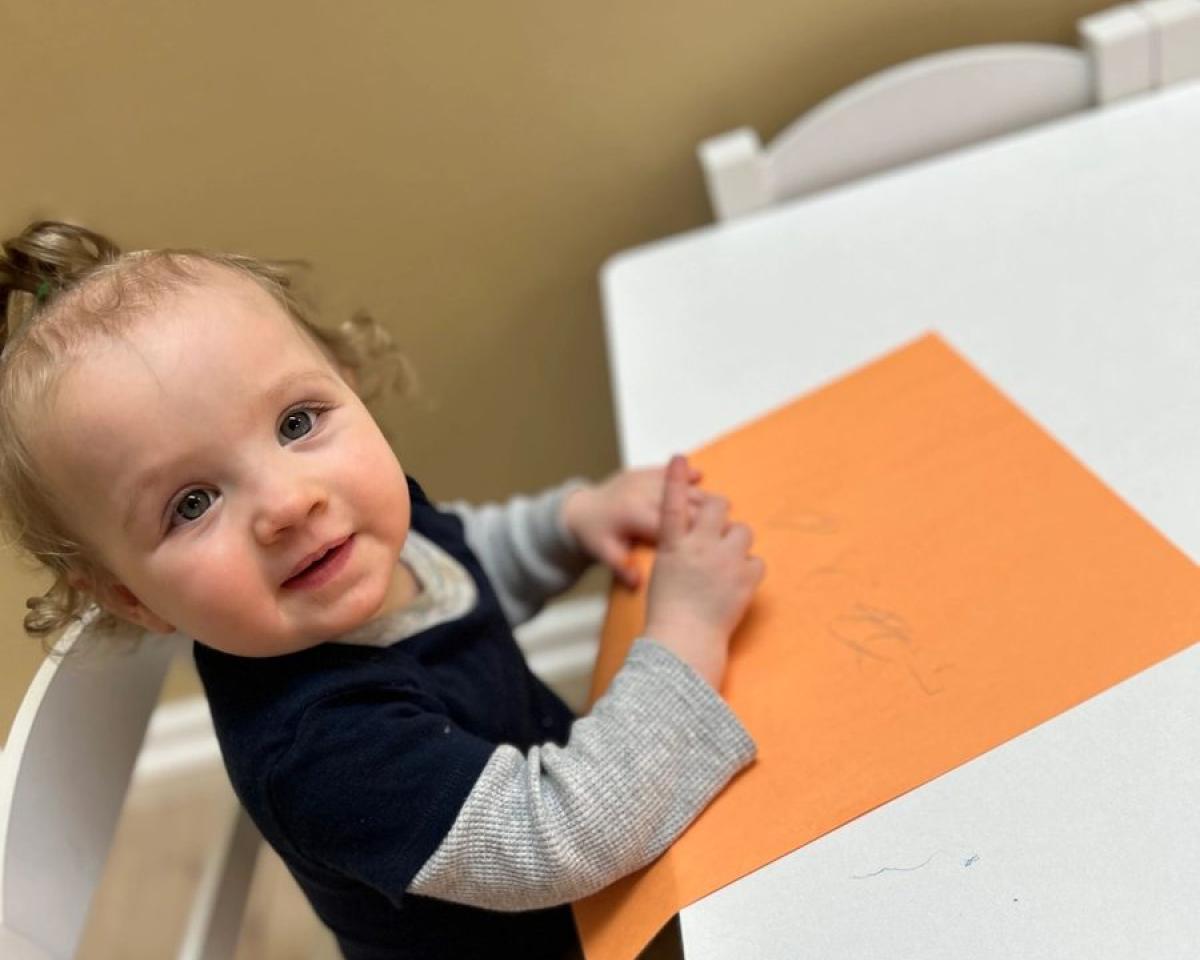A baby exploring coloured paper at the table